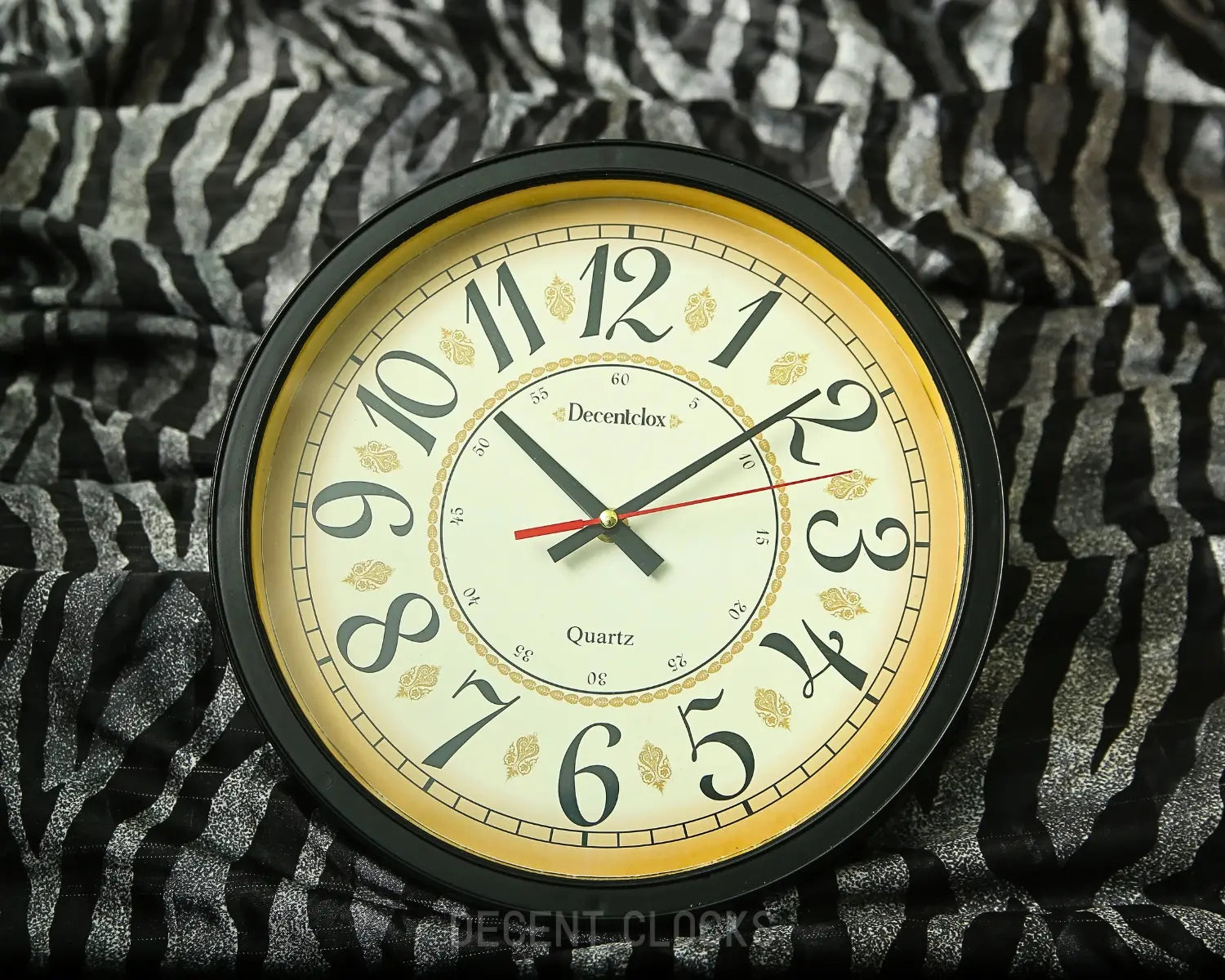 Round wall clock with black frame and white face on a patterned fabric background